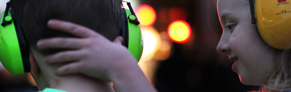 Two kids wearing ear protection headsets.