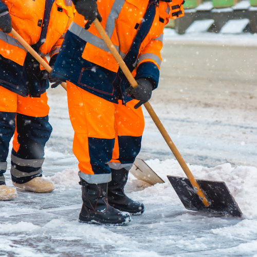 Communal services workers sweep snow from road in winter.