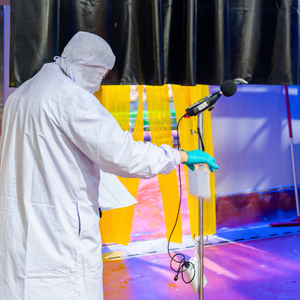 An industrial hygiene specialist in white PPE using a sound level meter to monitor noise pollution levels near a production line in a poultry processing plant.